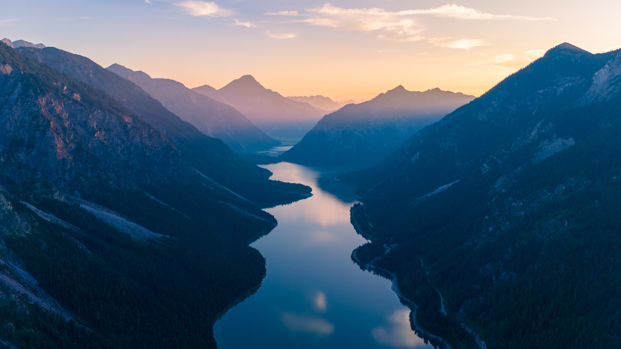 Quiet water between mountain ridges at twilight