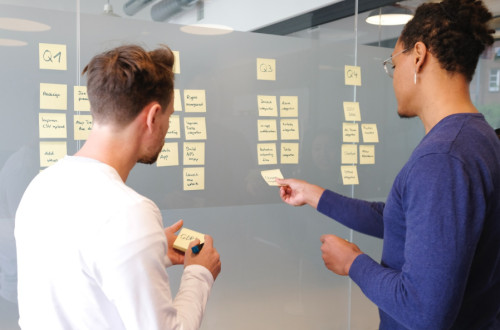 Project managers organizing post it notes on glass